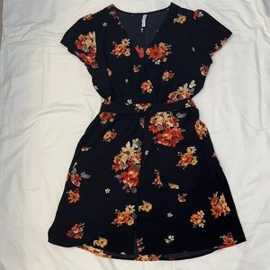 Black floral dress with a waist tie, pockets, and buttons.